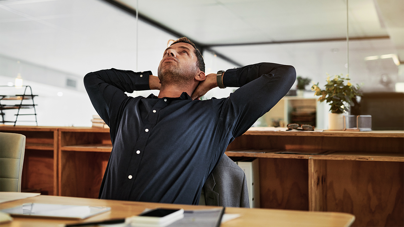 Man siting at desk stretching his back