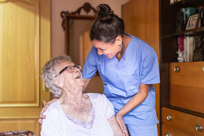 Happy Senior woman laughing with her caregiver at home.