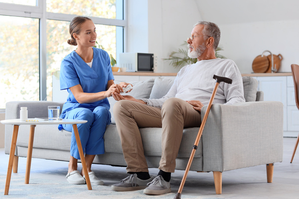 Senior man with nurse taking pill at home